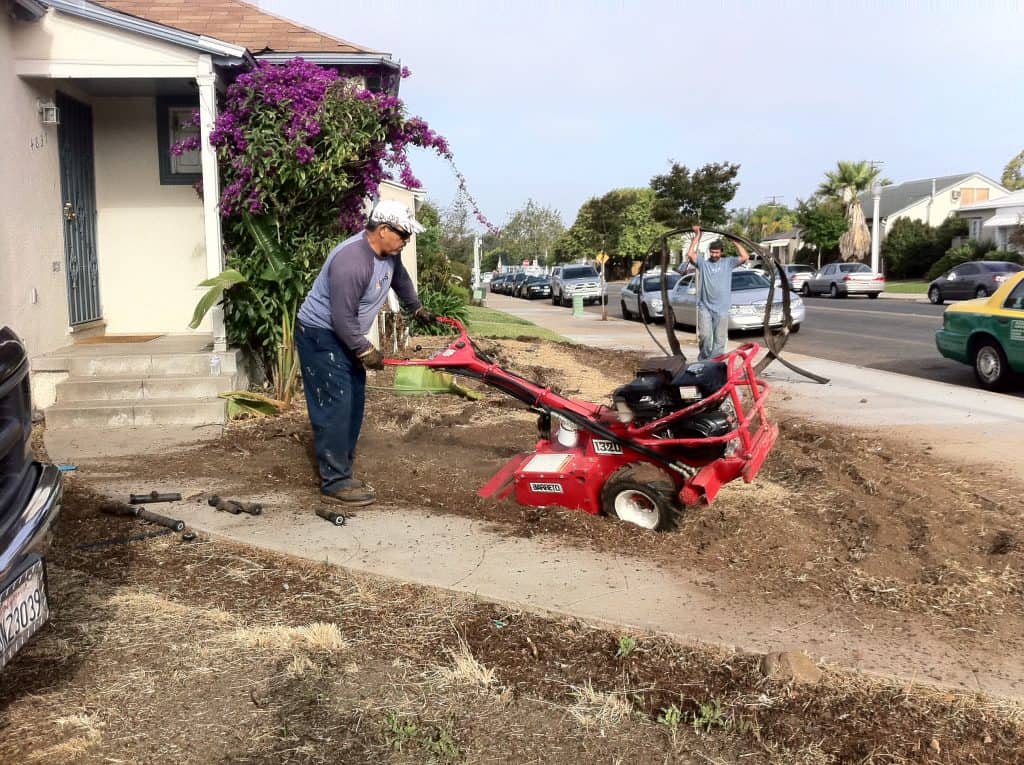 Man with a red tiller on his front yard